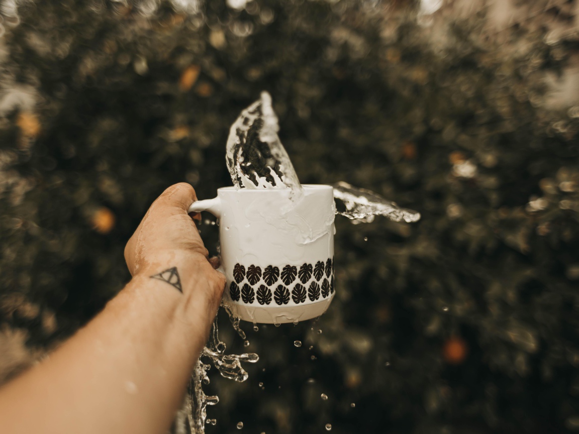 Чашка с водой в руке с татуировкой 