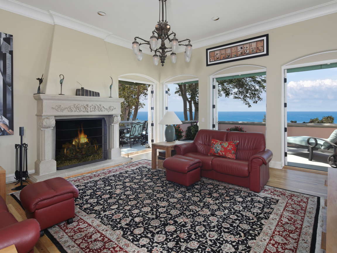 Гостиная с кожаным диваном, большими окнами и камином 