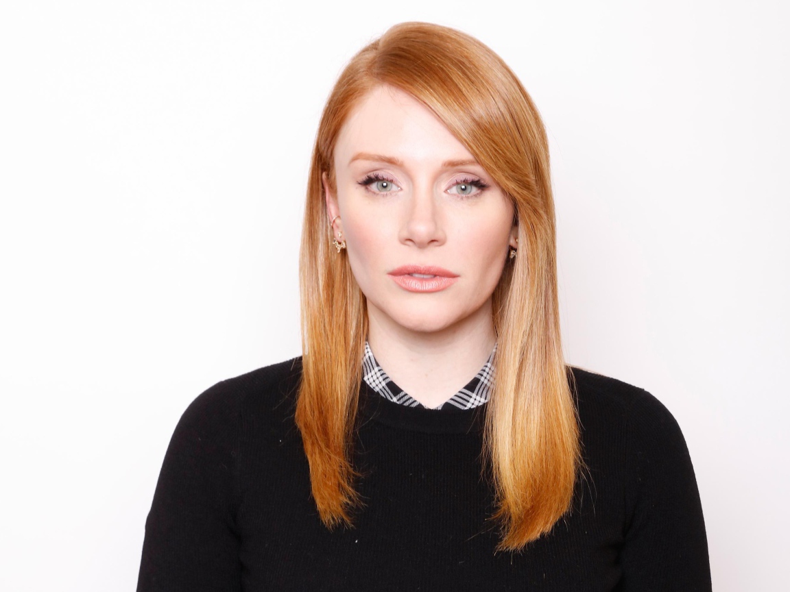 Рыжеволосая актриса Брайс Даллас Ховард в черном свитере на белом фоне