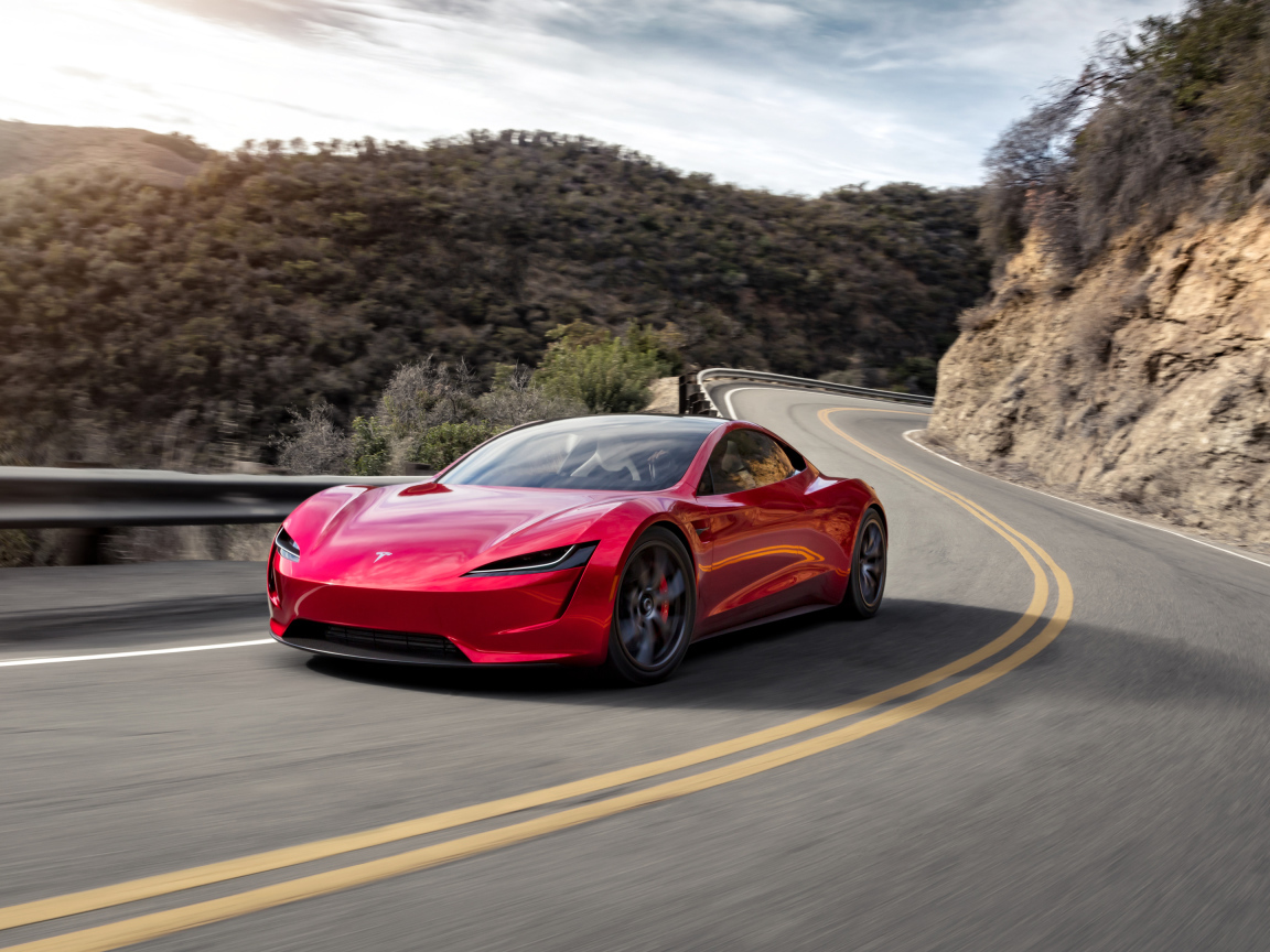 Красный автомобиль Tesla Roadster на трассе у гор 