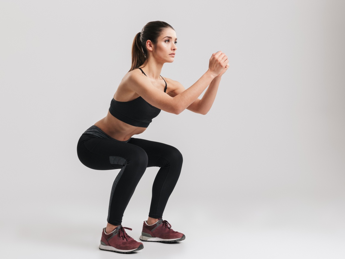 Девушка занимается гимнастикой на сером фоне