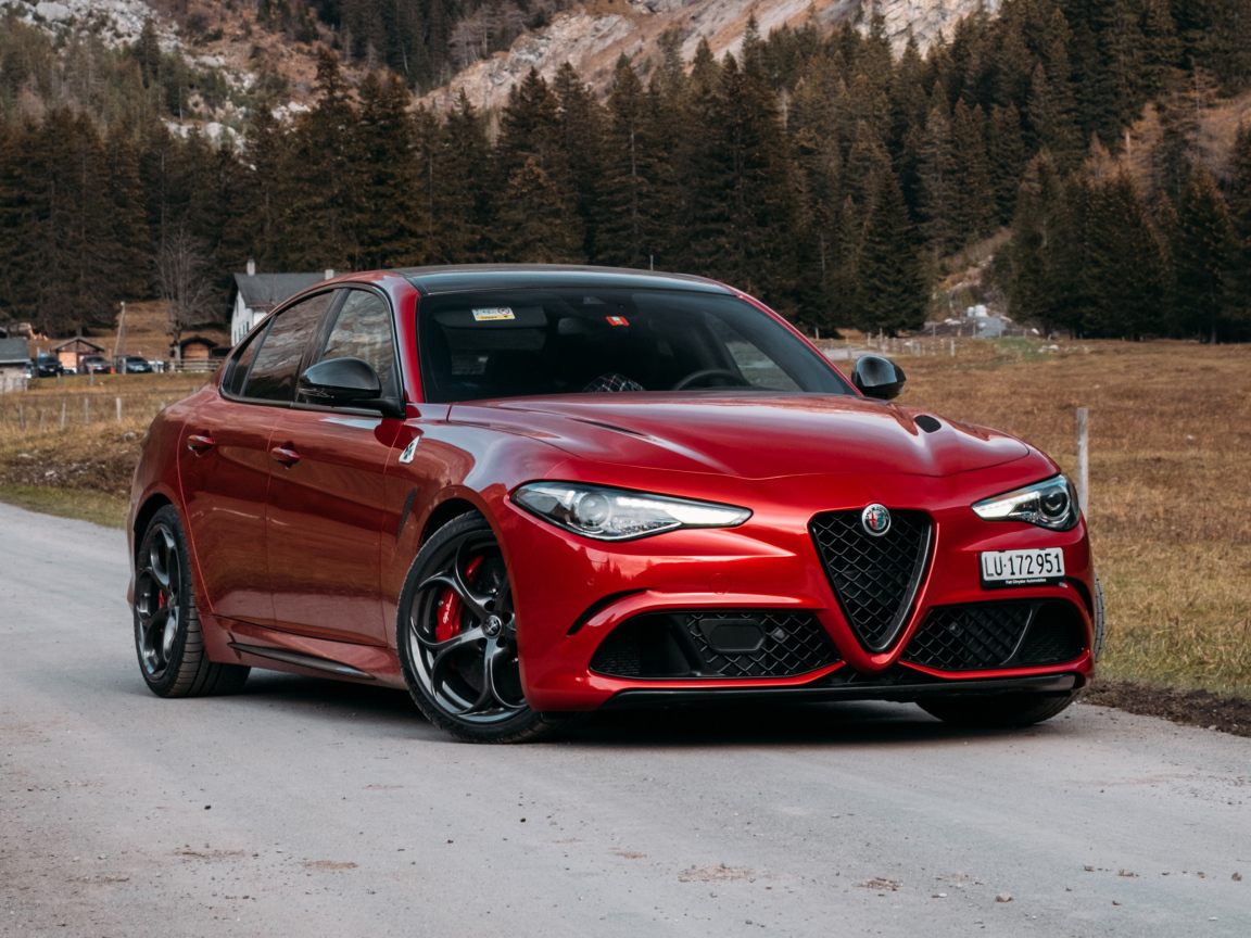 Красный автомобиль Alfa Romeo Giulia Quadrifoglio 2021  года на фоне гор