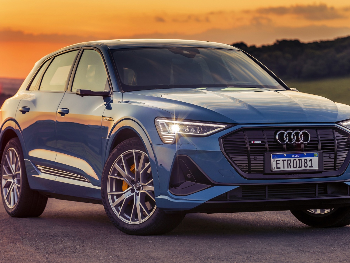 Синий автомобиль Audi E-Tron 55 Quattro S Line 2020 года на закате
