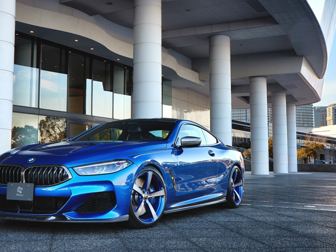 Синий автомобиль BMW M850i XDrive Coupe 2020 года у здания 