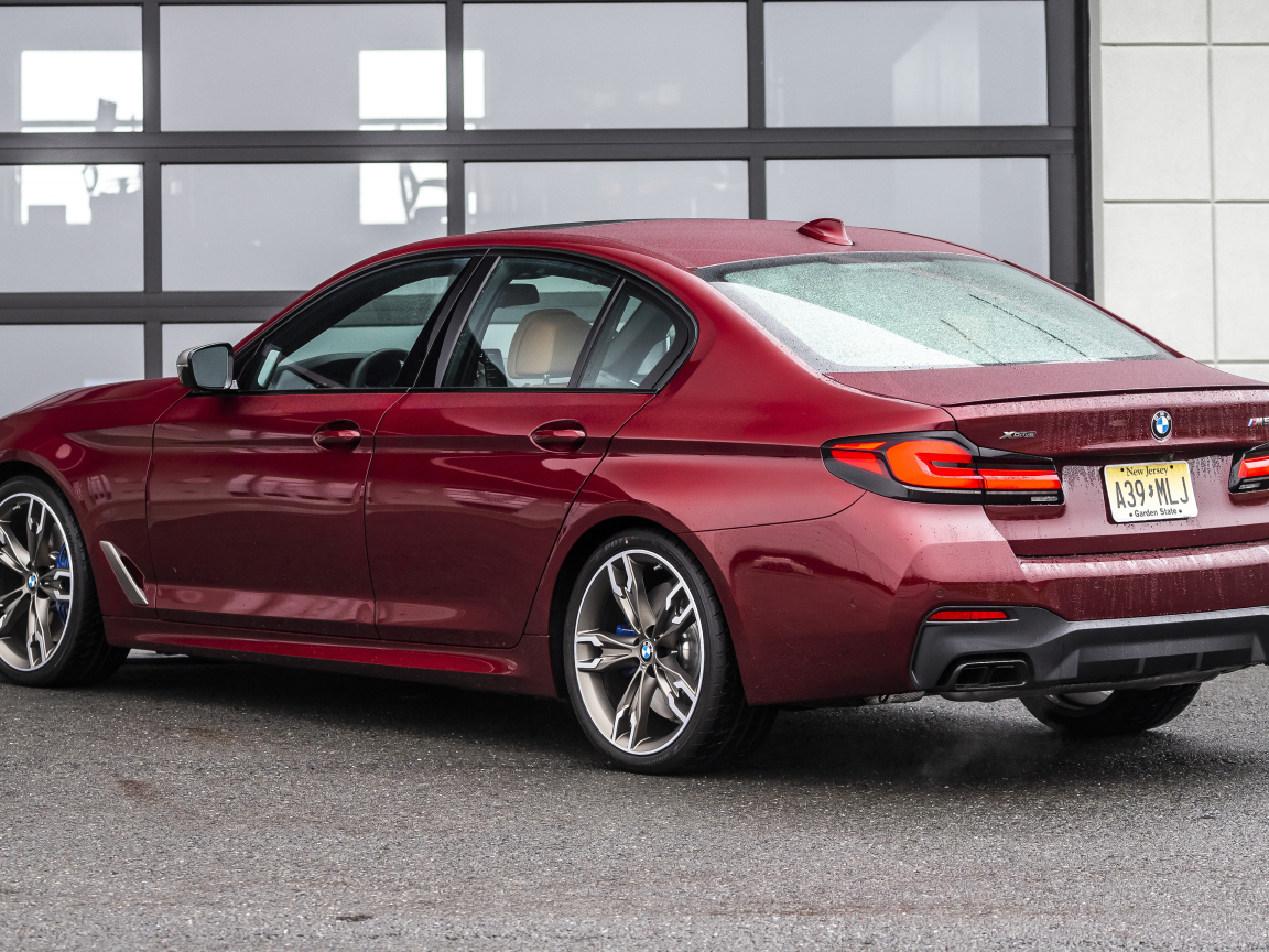 Красный автомобиль BMW M550i XDrive, 2021 года вид сзади