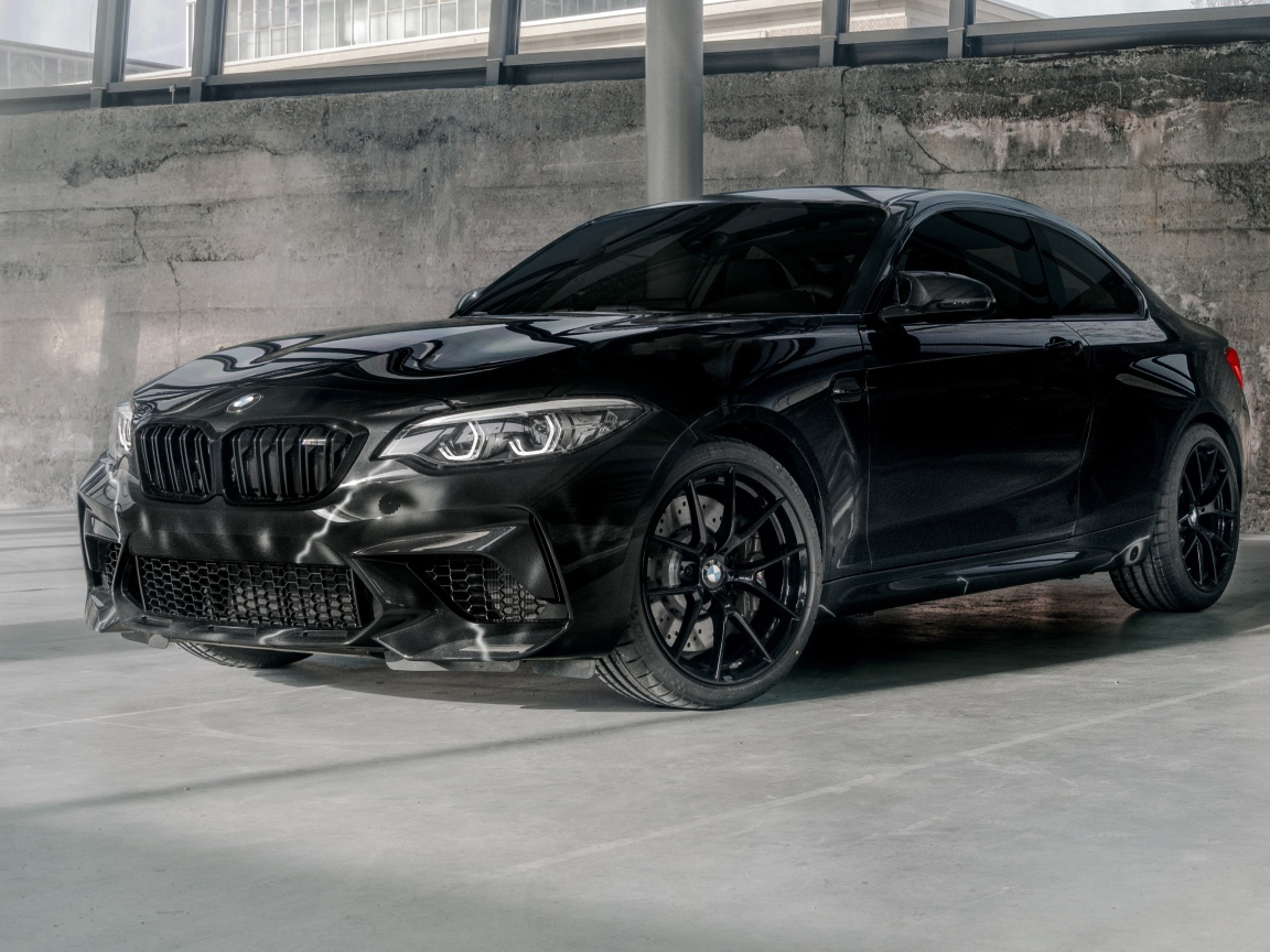 Черный автомобиль  BMW M2, 2020 года у бетонной стены