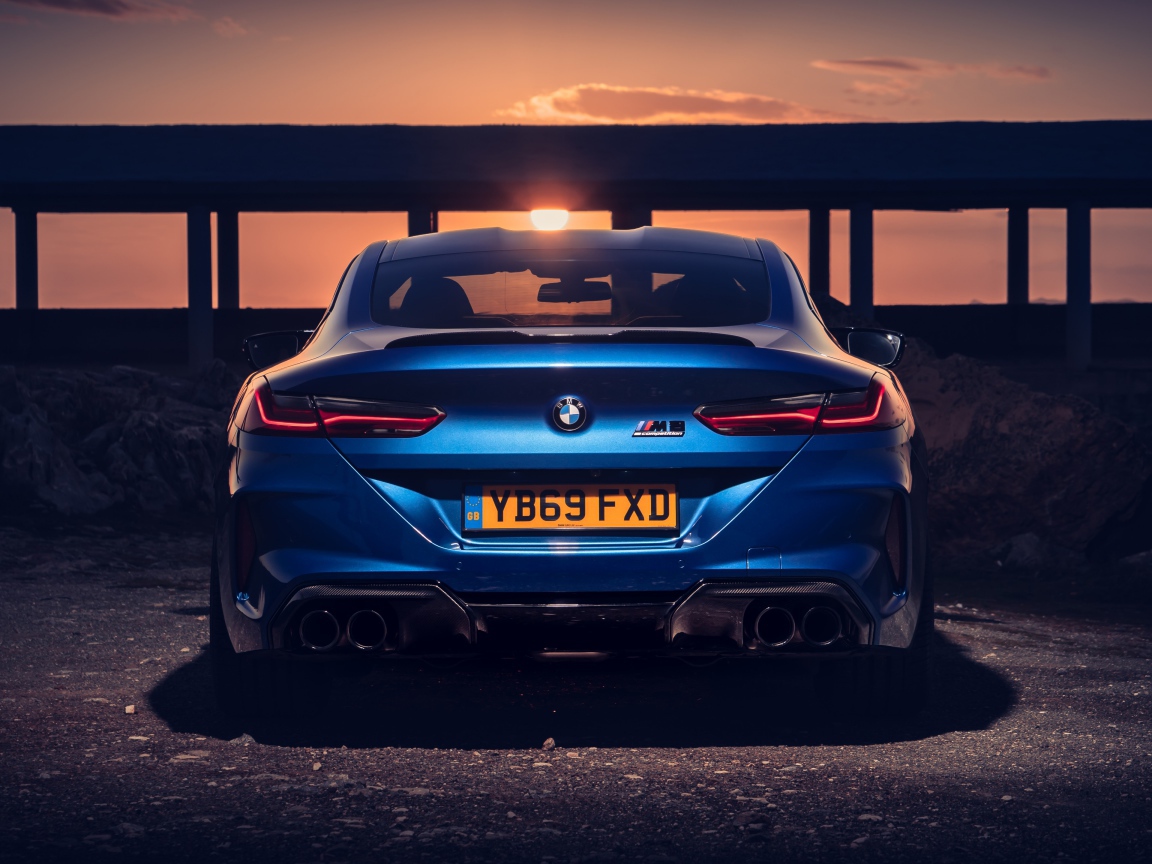Синий автомобиль BMW M8, 2019 года на фоне заката 