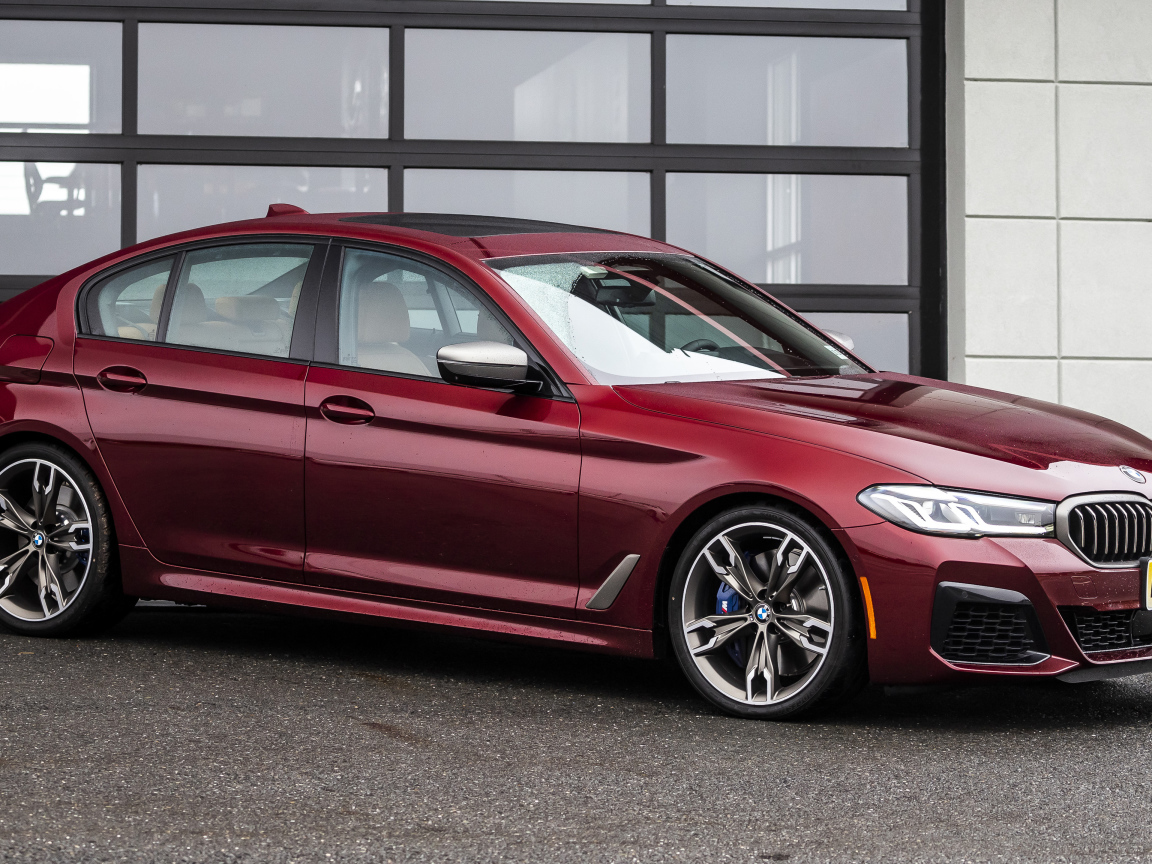 Красный автомобиль BMW M550i XDrive, 2021 года у гаража