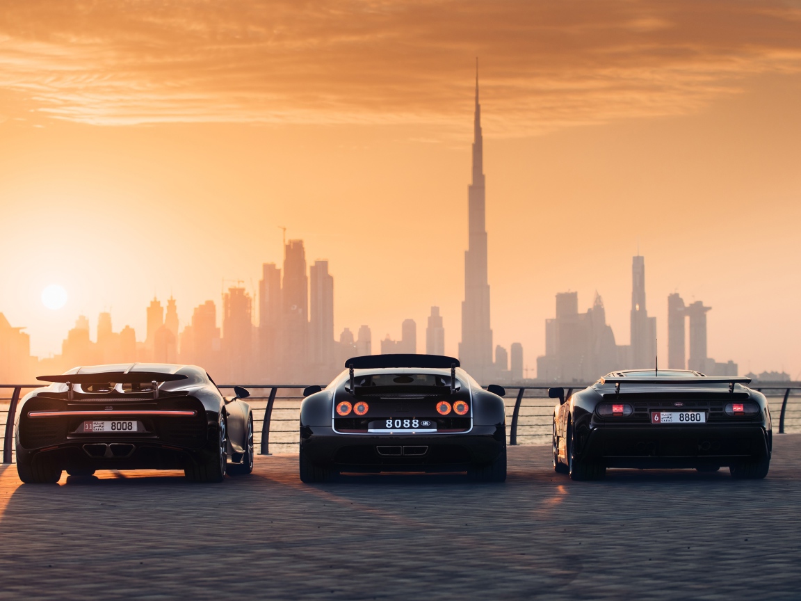Три автомобиля  Bugatti Veyron и Bugatti Chiron на фоне заката