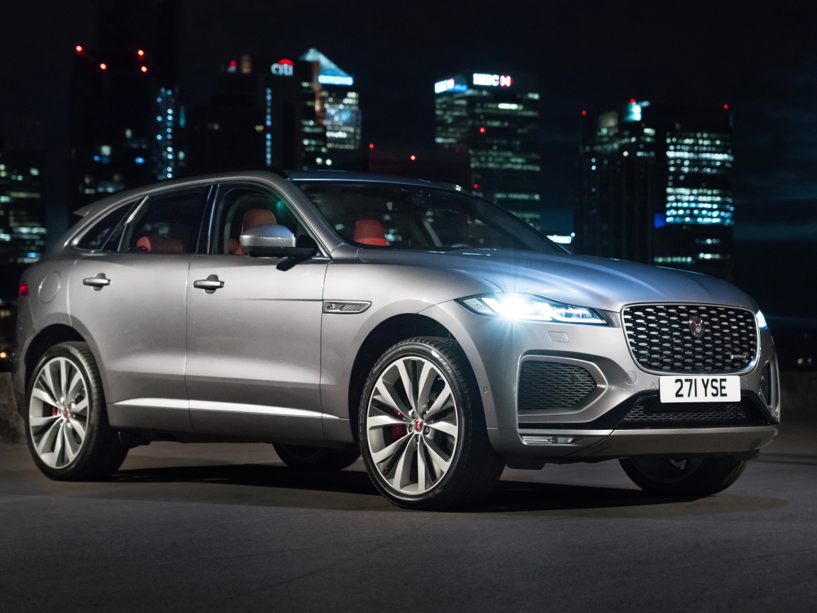 Серебристый Jaguar F-Pace R-Dynamic 2020 года на фоне ночного мегаполиса 