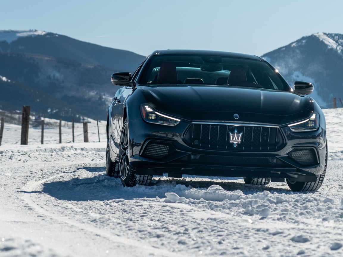 Черный автомобиль Maserati Ghibli S Q4, 2020 года едет по заснеженной дороге