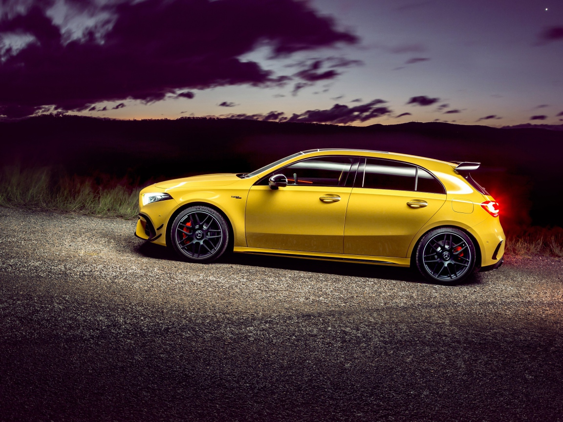 Желтый автомобиль Mercedes-AMG A 45 S, 2020 года на дороге в сумерках 