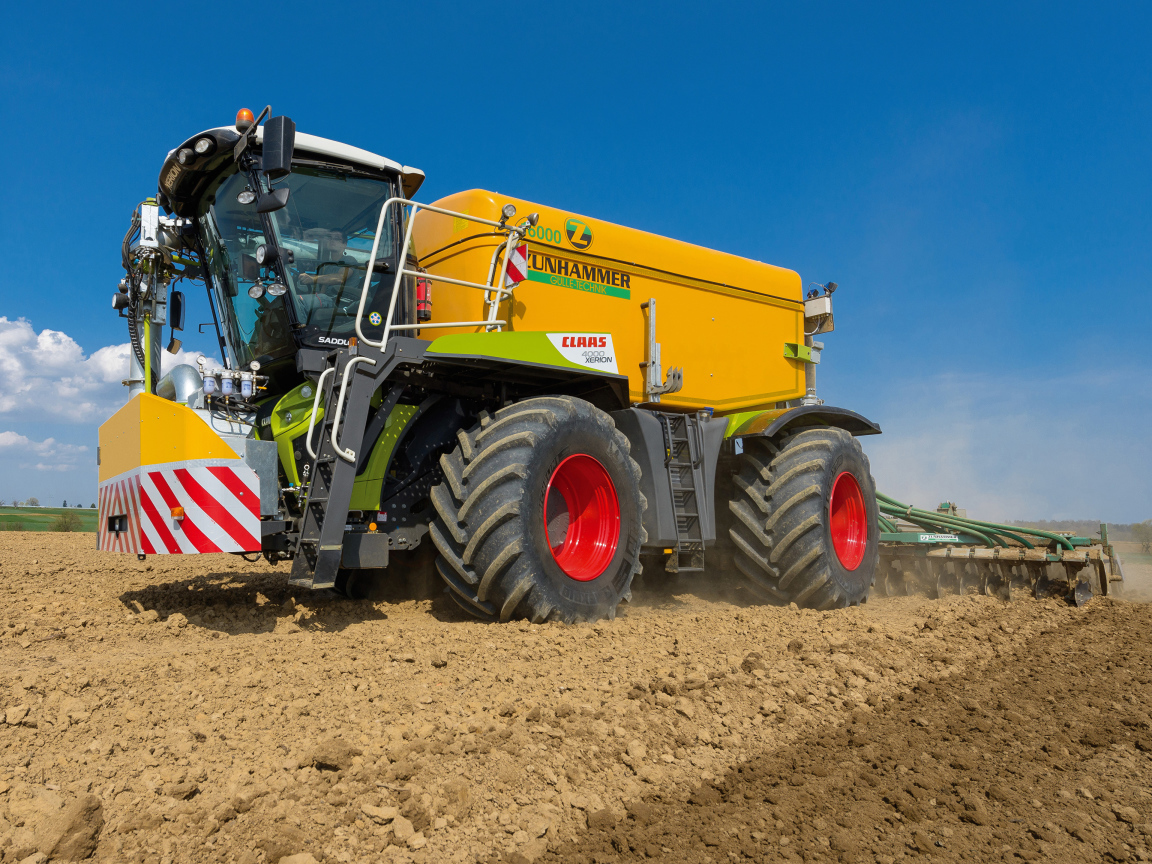 Большой комбайн пашет поле под голубым небом