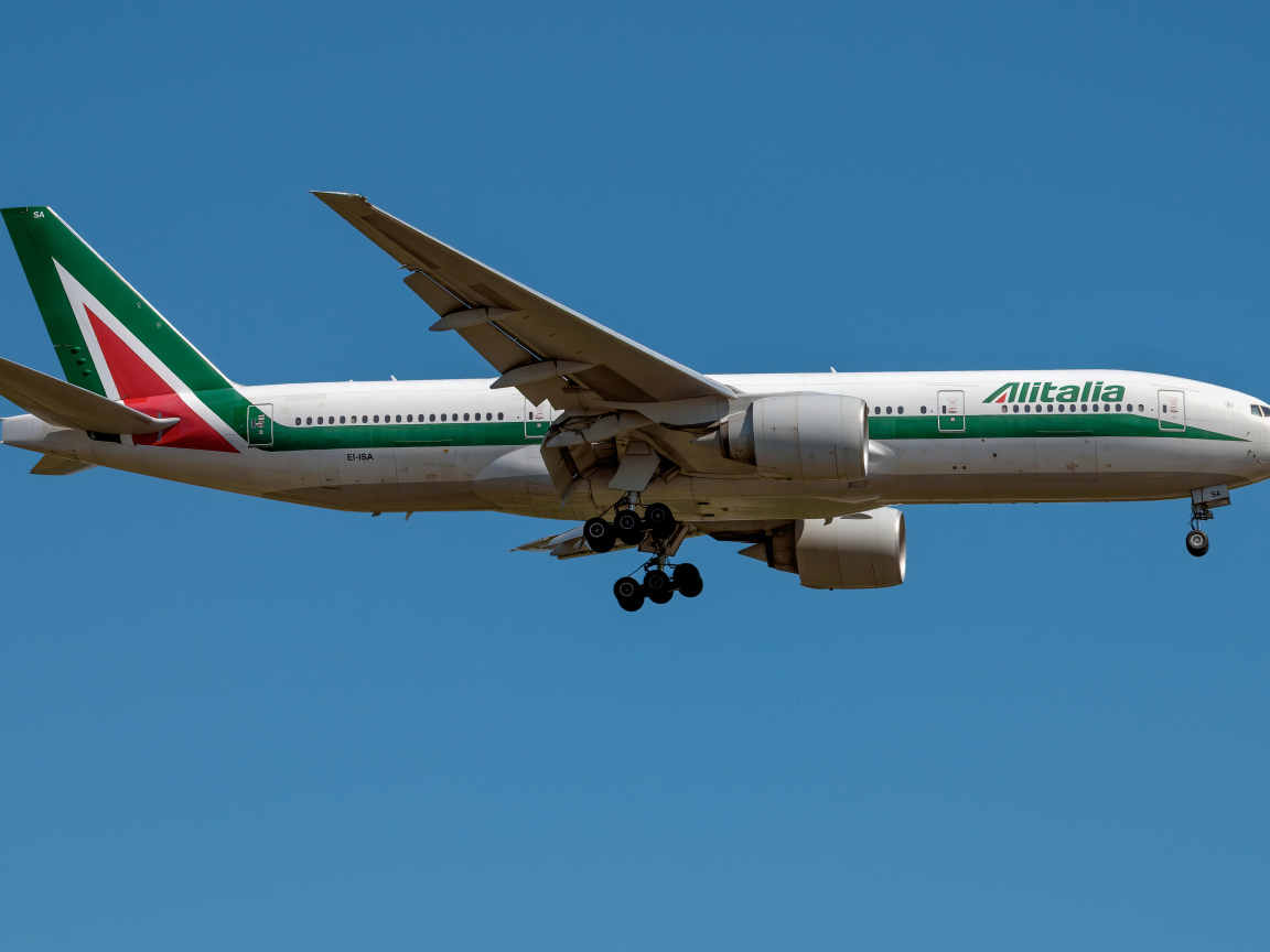 Пассажирский  самолет авиакомпании Alitalia в голубом небе 