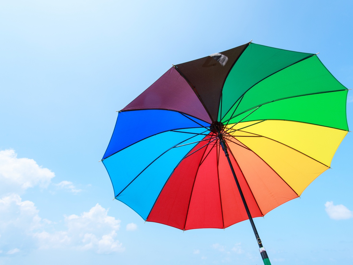 Разноцветный зонт на фоне голубого неба 