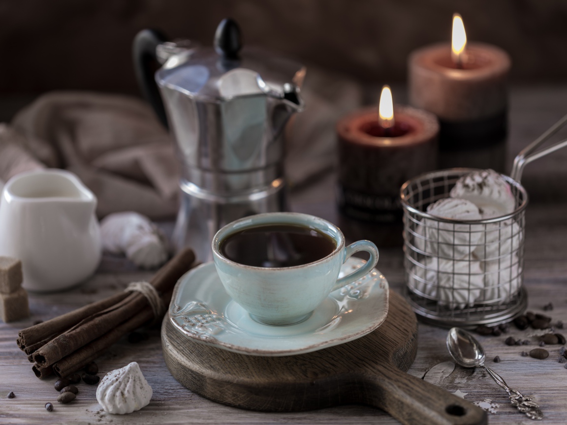 Чашка эспрессо на столе с корицей, зефиром и зажженными свечами