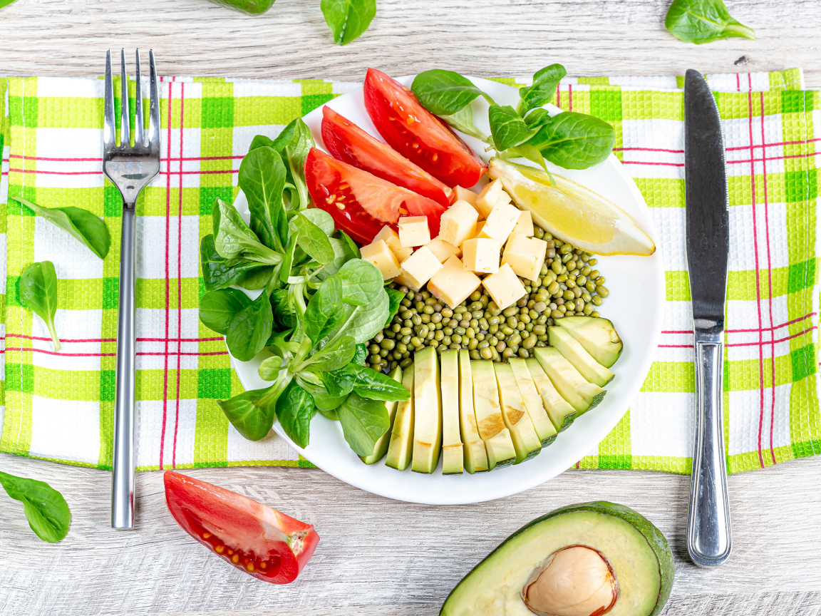 Аппетитные  свежие овощи с сыром и лимоном на тарелке 