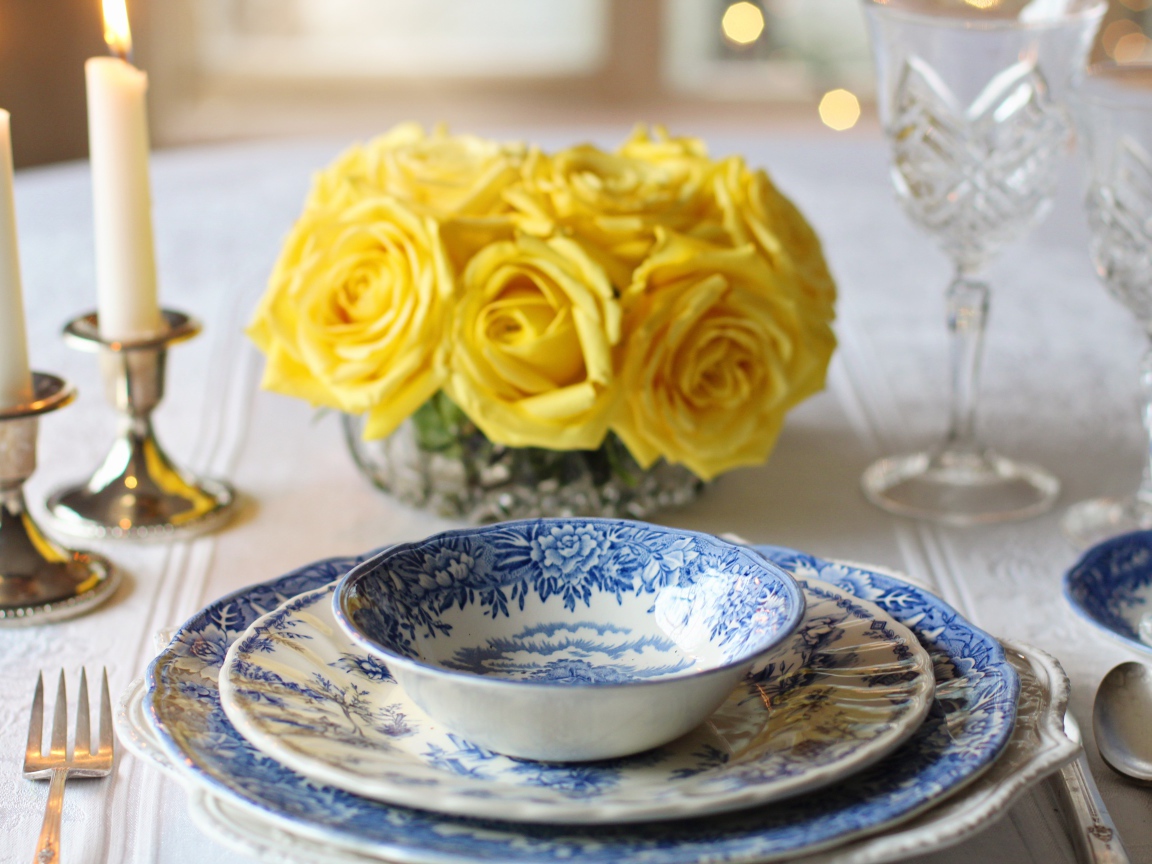 Красивая посуда на столе с букетом роз и свечами