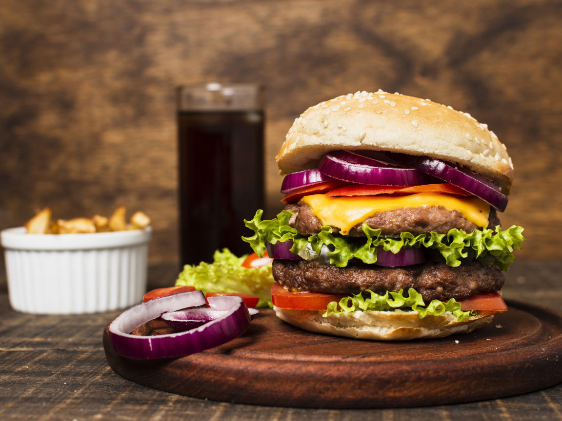 Большой гамбургер на столе с колой и картофелем фри 