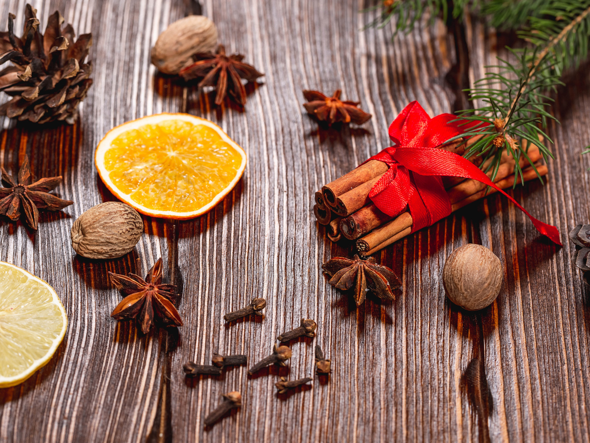 Корица на столе с орехами, бадьяном, сушеными апельсинами и гвоздикой