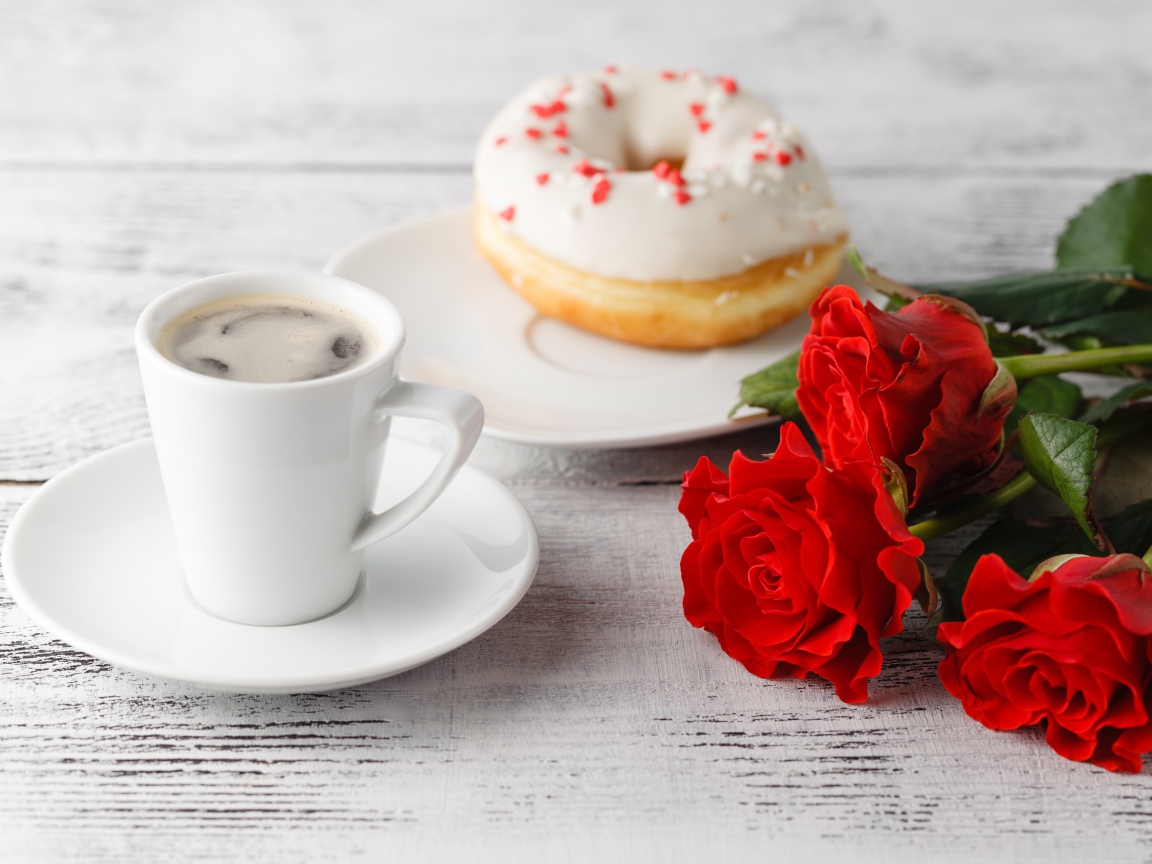 Чашка кофе, пончик и три красных розы на столе