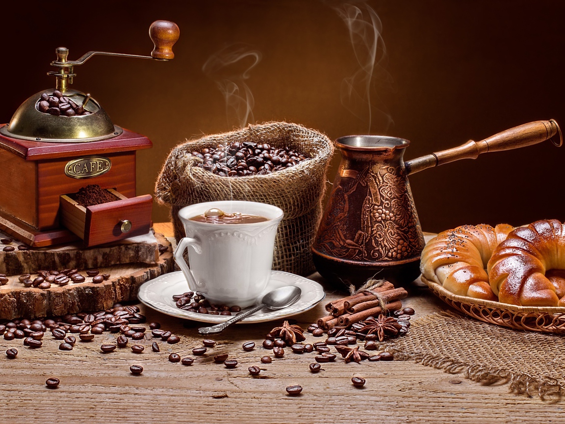 Чашка кофе на столе с круассанами и кофемолкой