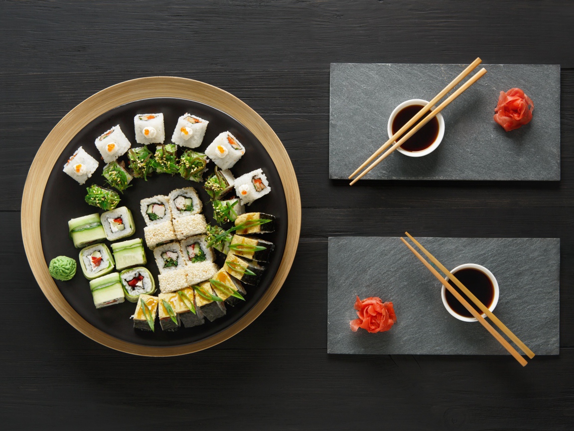 Вкусные  роллы на столе с соевым соусом и палочками 