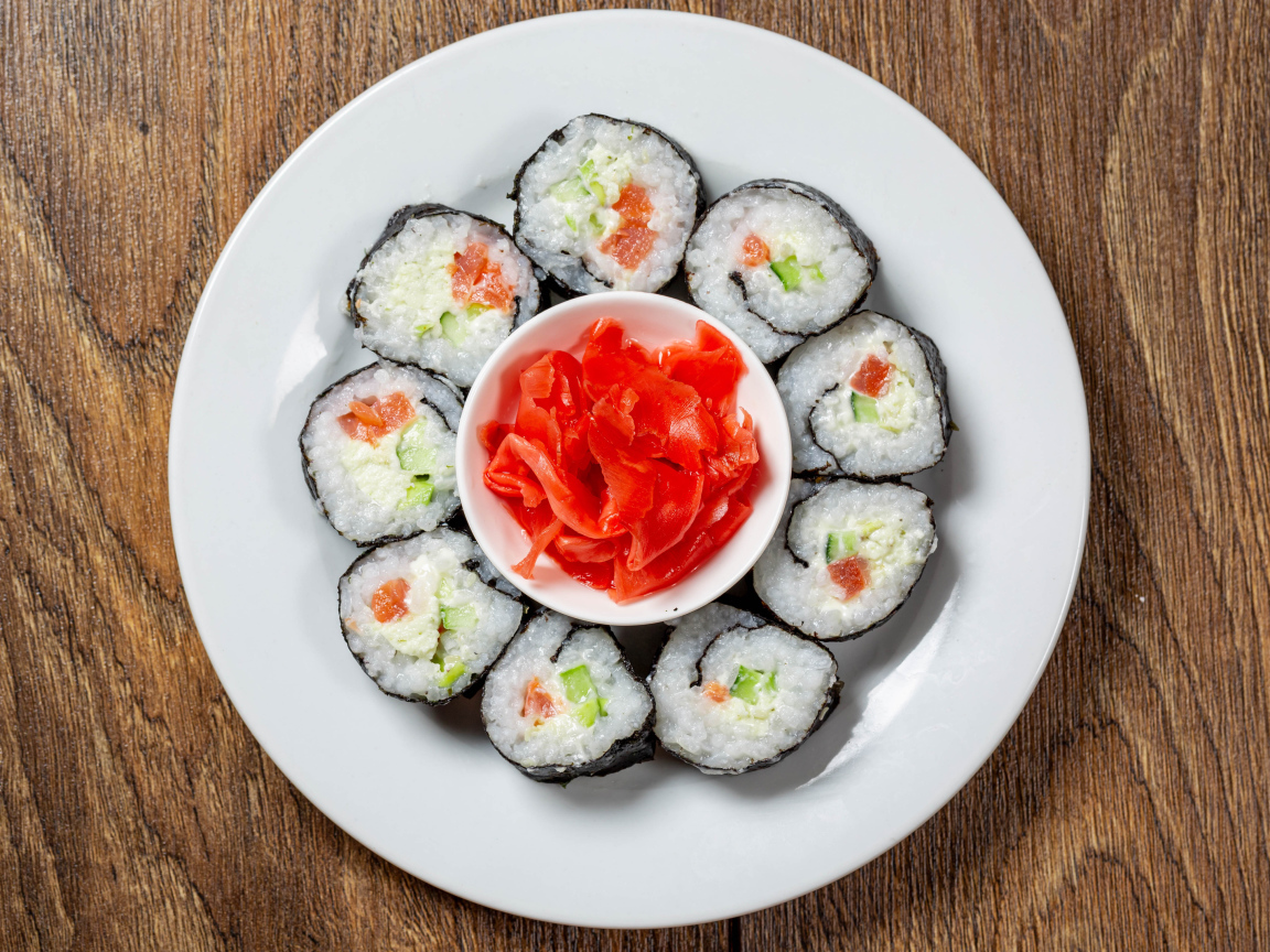 Вкусные суши на большой белой тарелке с имбирем