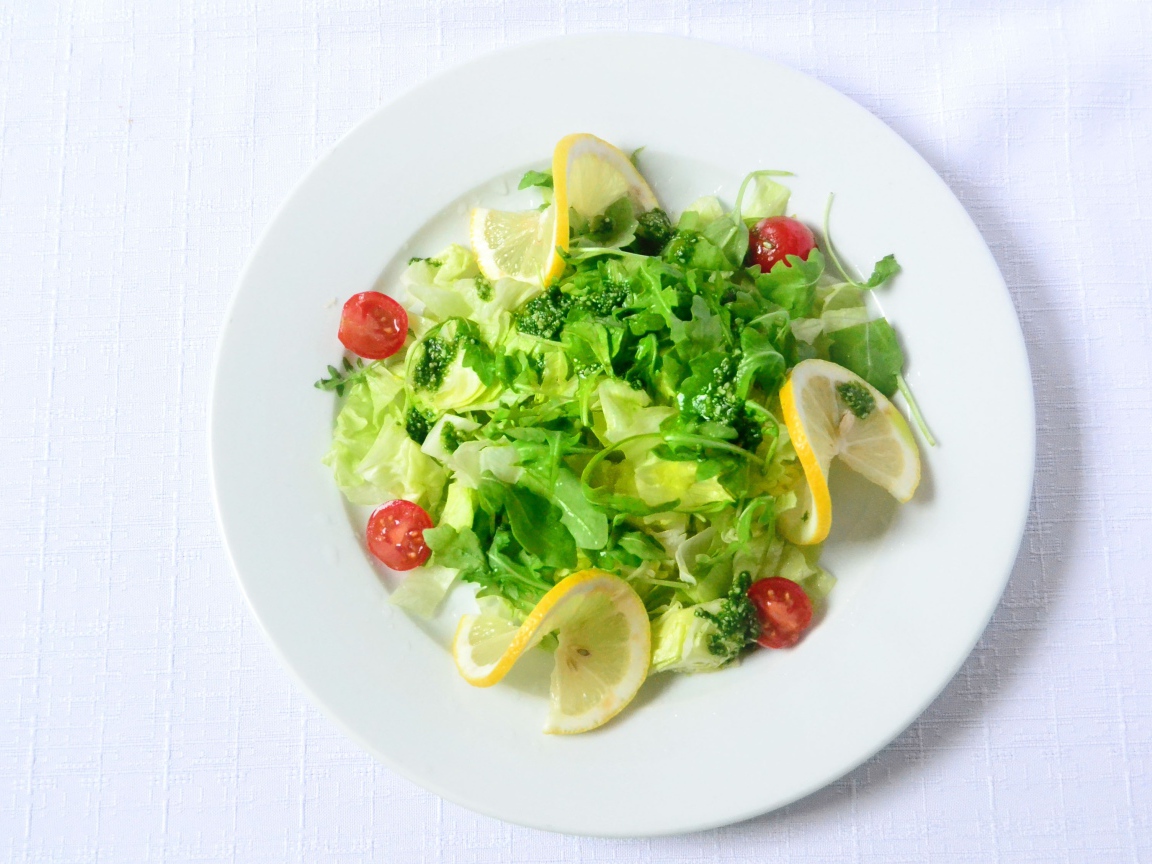 Салат из зелени с лимоном на белом фоне 