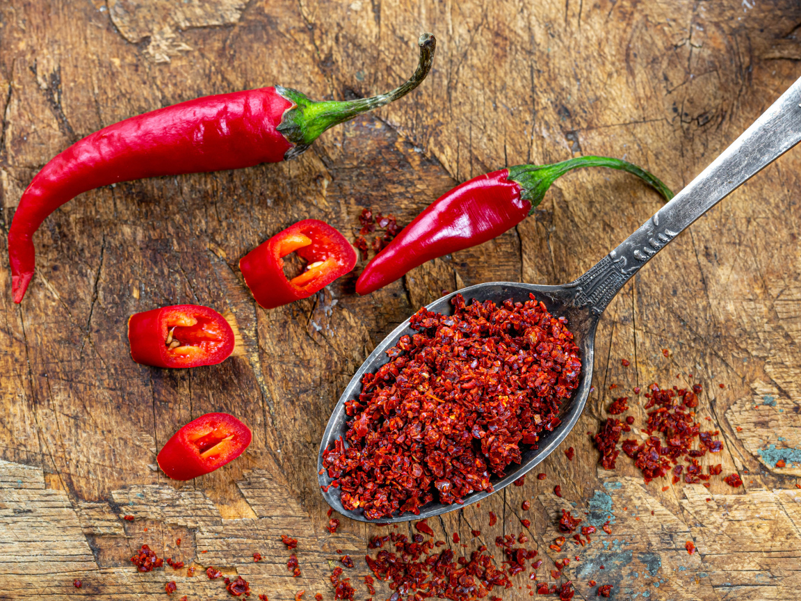 Молотый красный перец на ложке на столе 