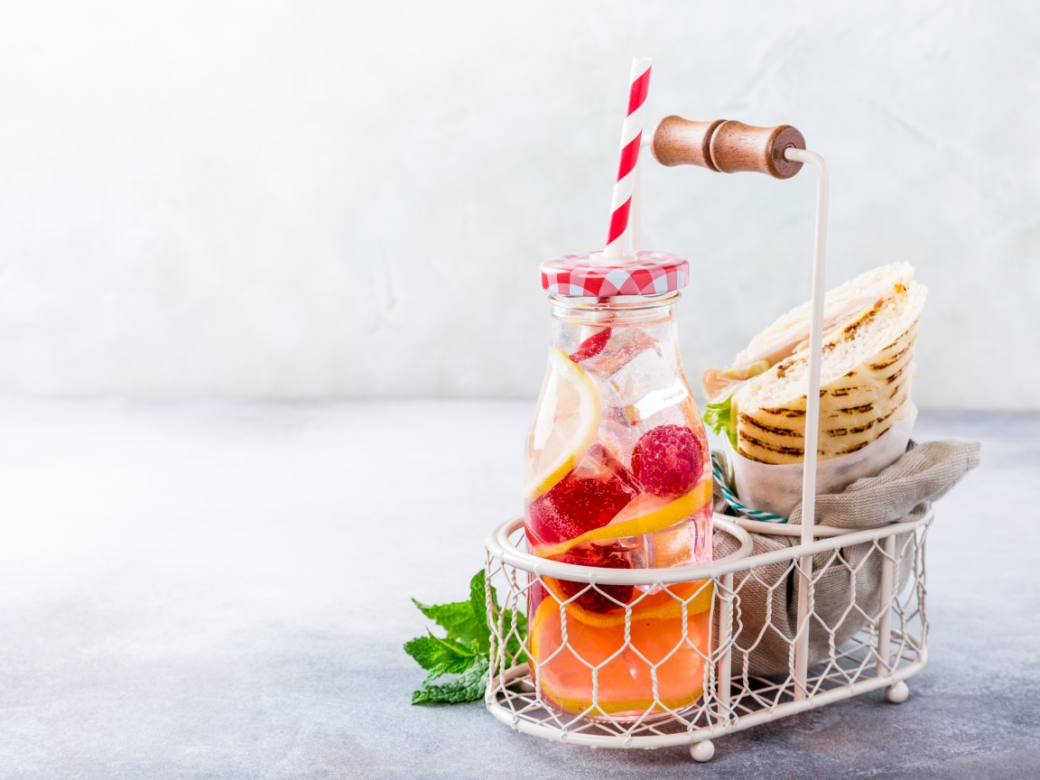 Банка с лимонадом в маленькой корзине с сэндвичем 