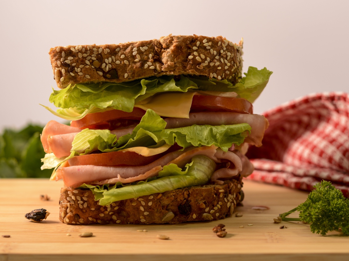 Большой бутерброд с ветчиной, сыром, помидорами и листьями салата 