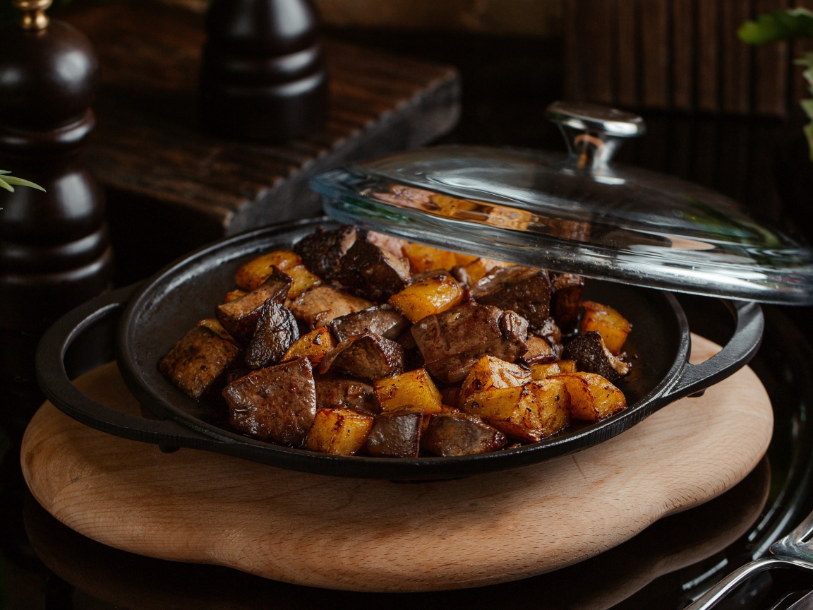 Печень с картофелем в сковороде на столе