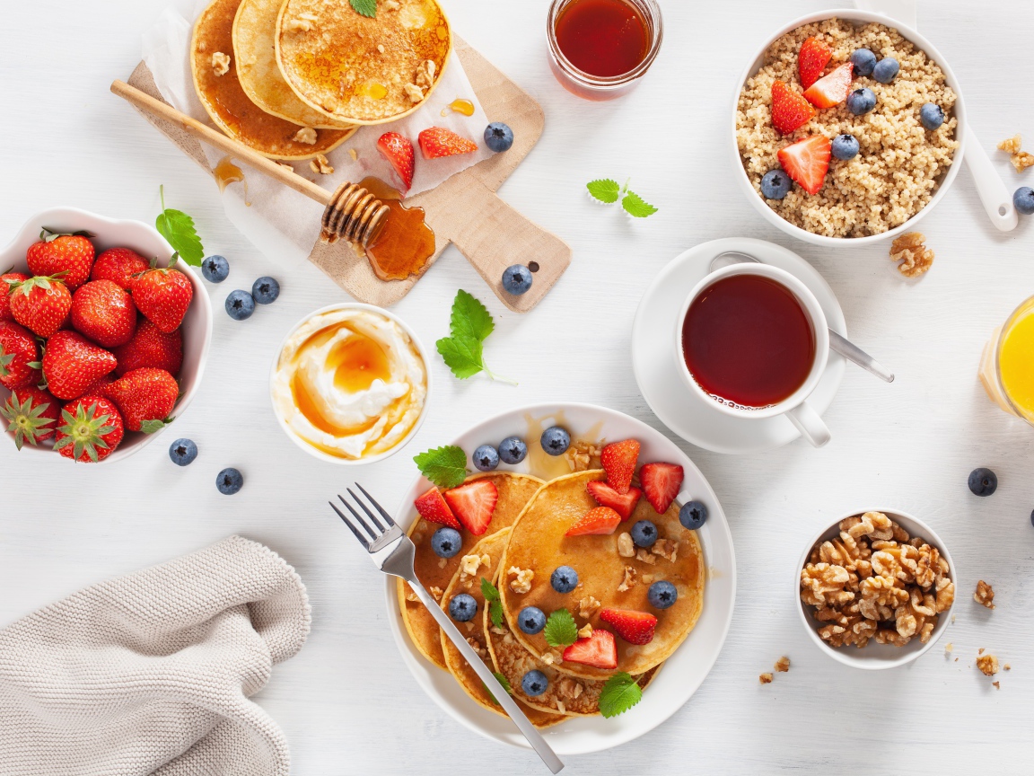 Оладьи с ягодами на столе с соком, чаем и мюсли на завтрак 