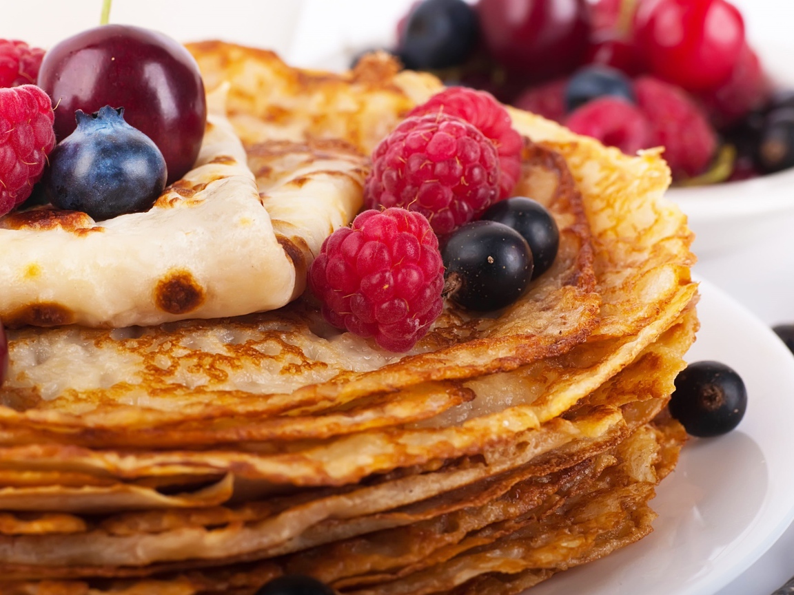 Pancakes with blueberries and raspberries on a white plate