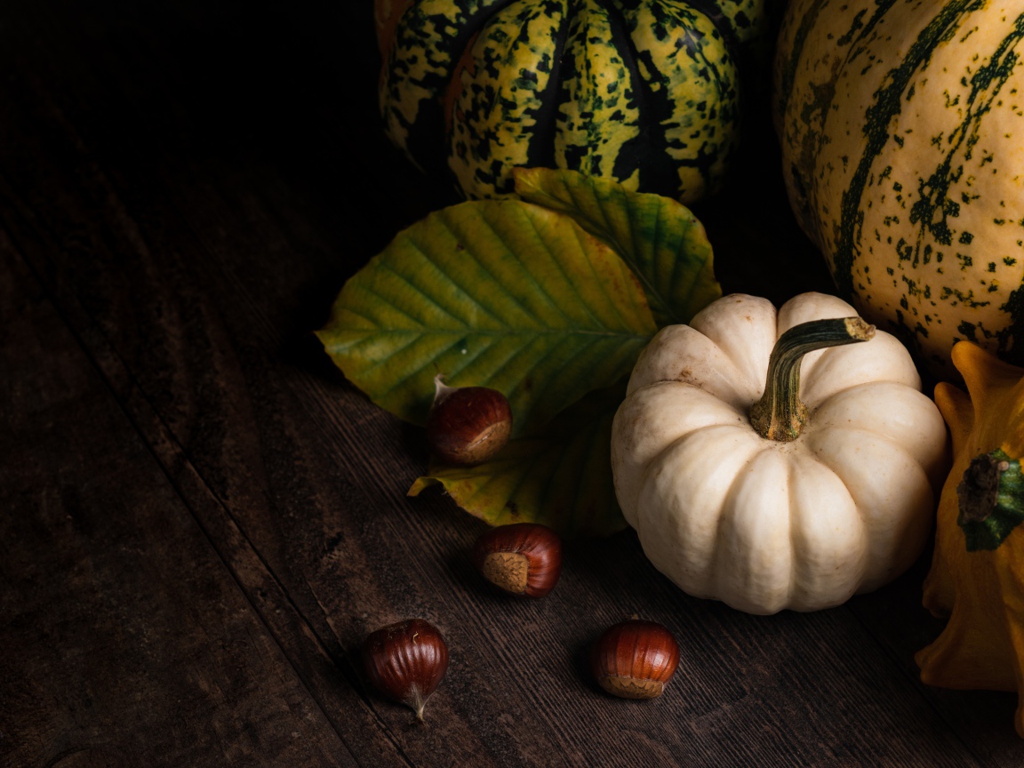 Тыква с каштанами на деревянном столе 