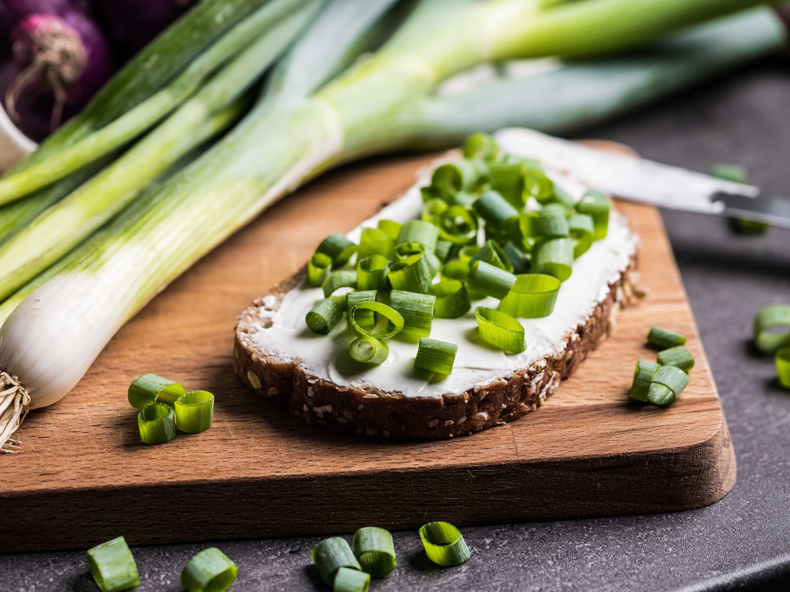 Бутерброд с маслом и зеленым луком на столе 