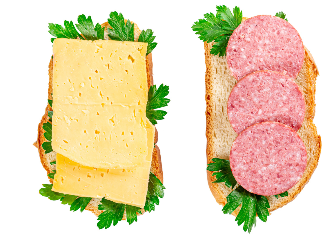 Два бутерброда с сыром,колбасой,петрушкой на белом фоне