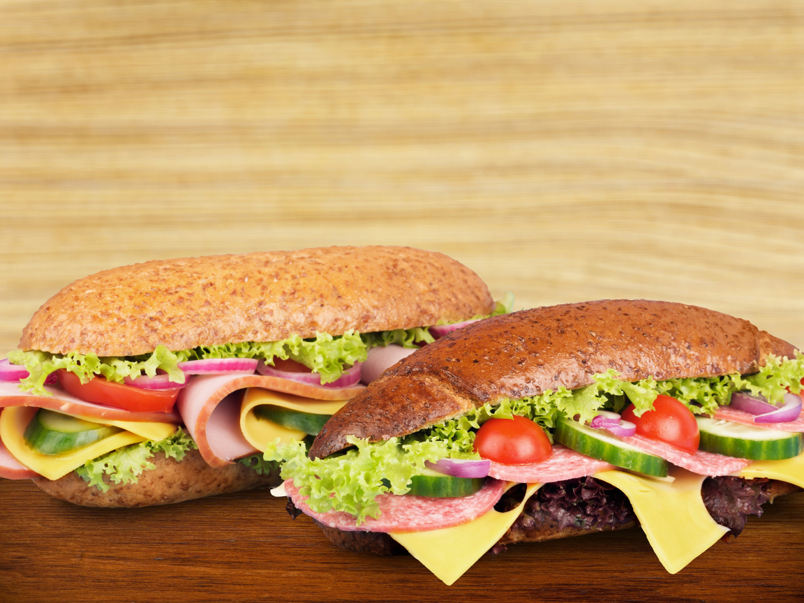 Два вкусных бутерброда с овощами и колбасой на столе 
