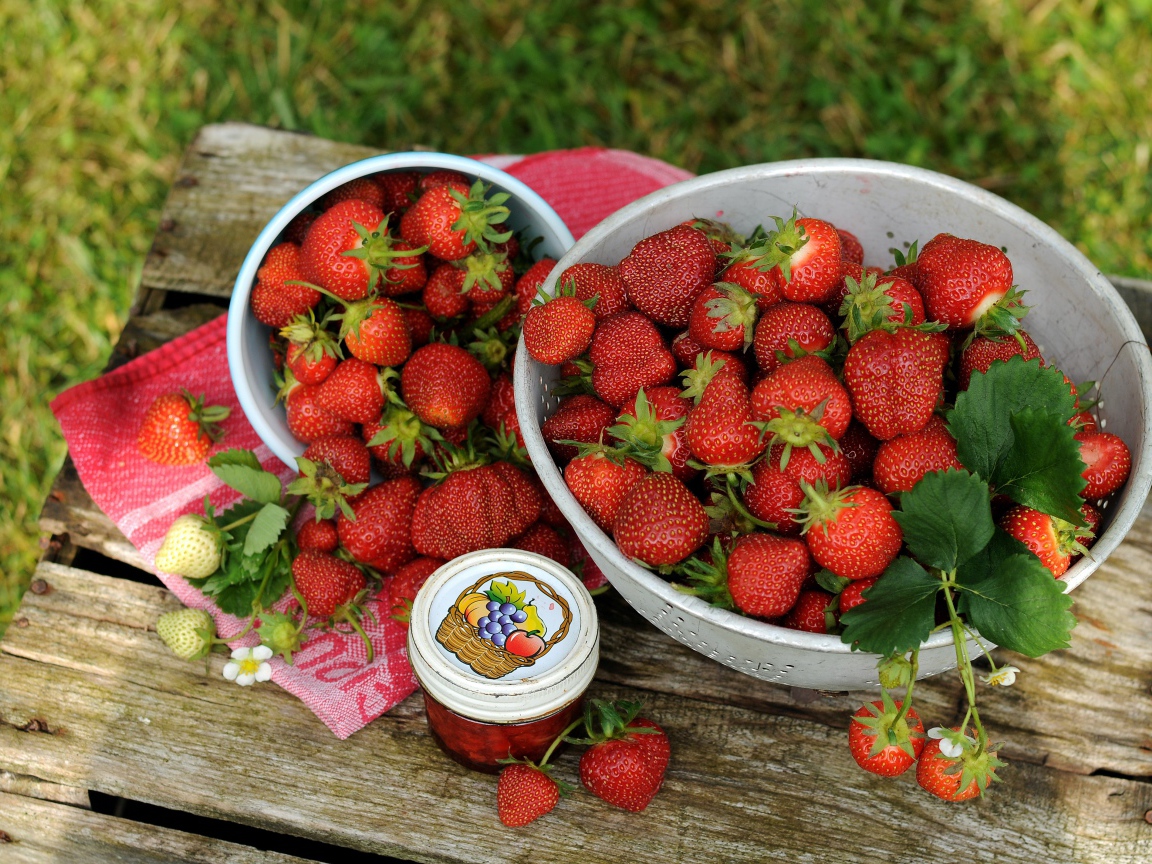 Много спелой ароматной клубники на столе с джемом 