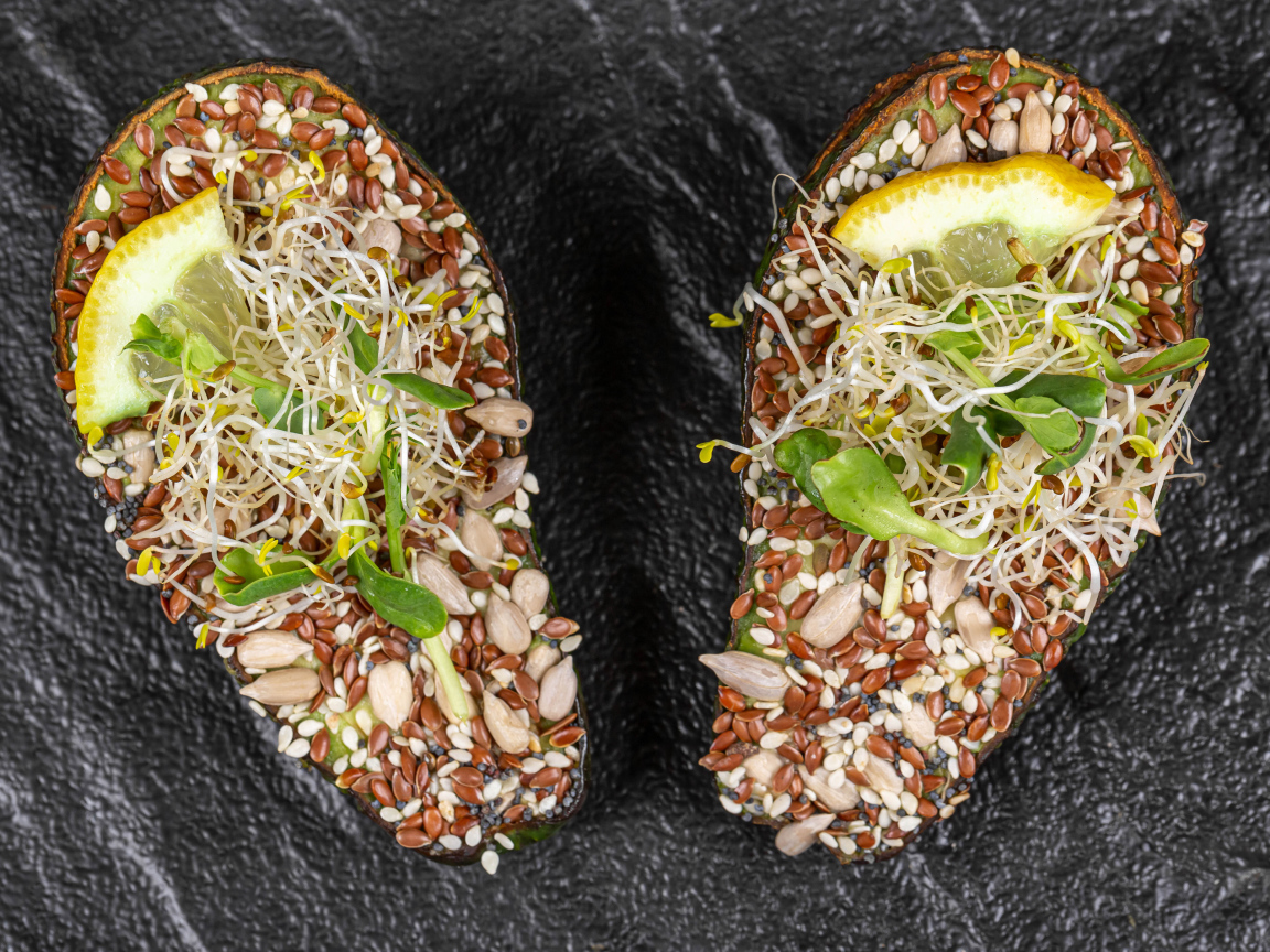 Половинки авокадо с проросшими зернами на столе