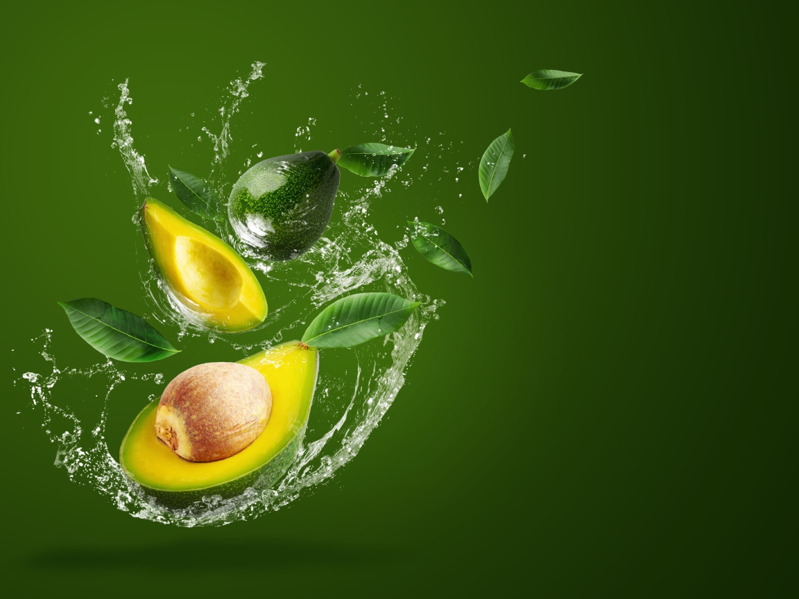 Авокадо в брызгах воды на зеленом фоне