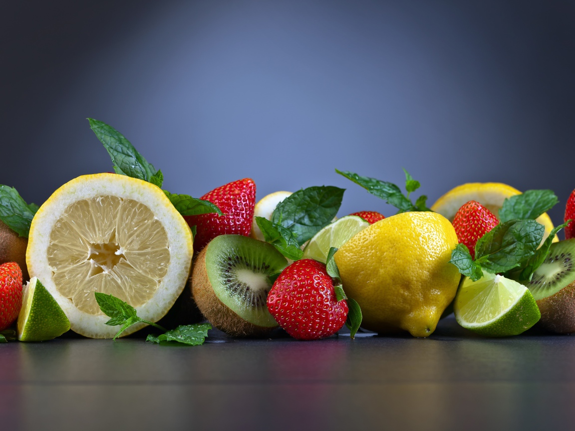 Лимоны на столе с киви и ягодами клубники 