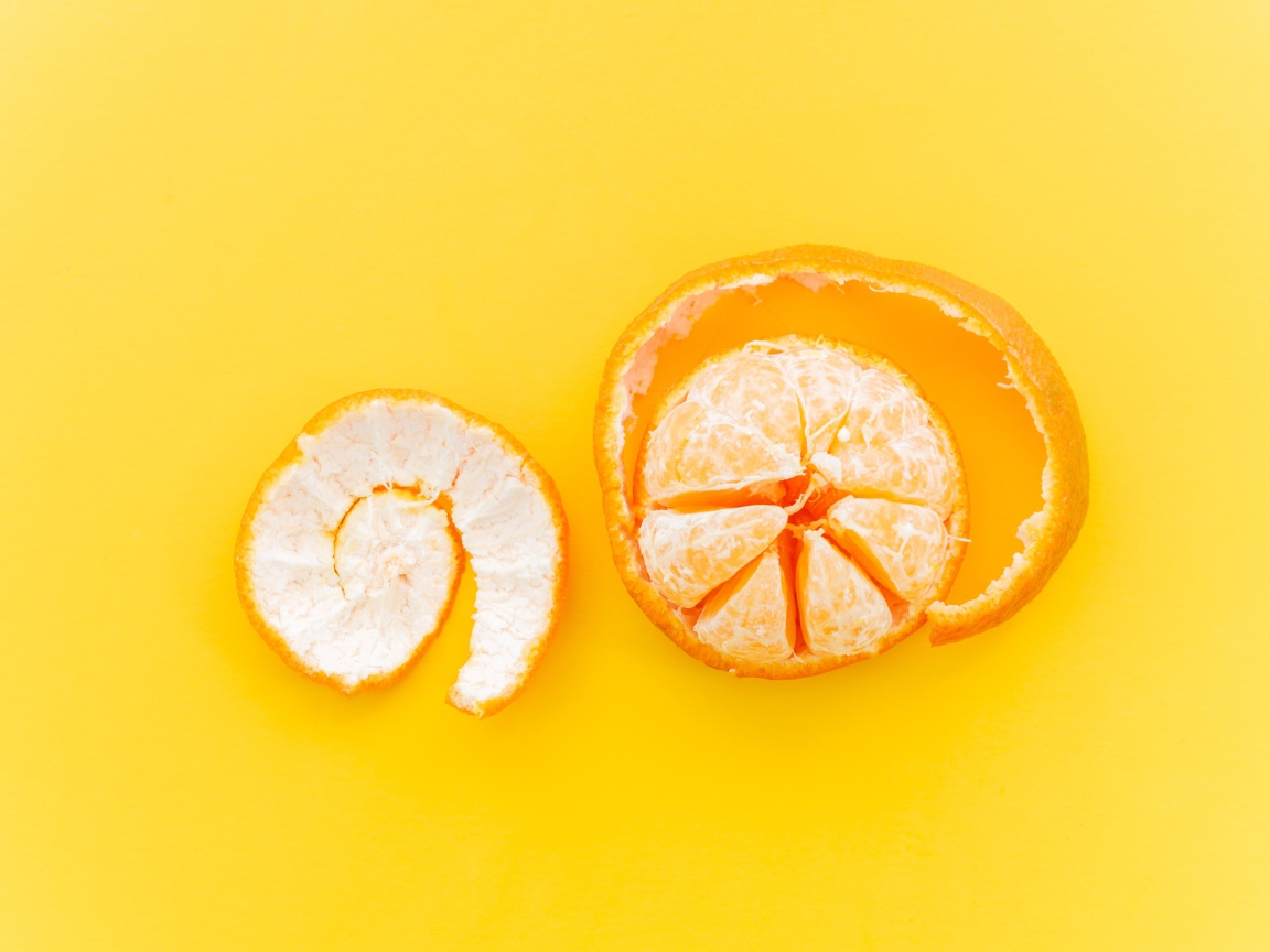 Очищенный мандарин с кожурой на желтом фоне 