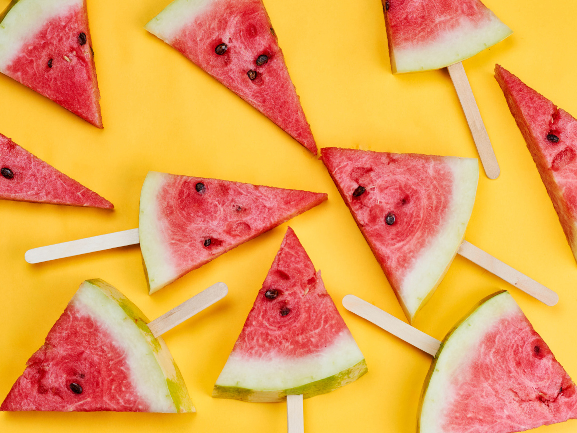 Pieces of watermelon on sticks on yellow background