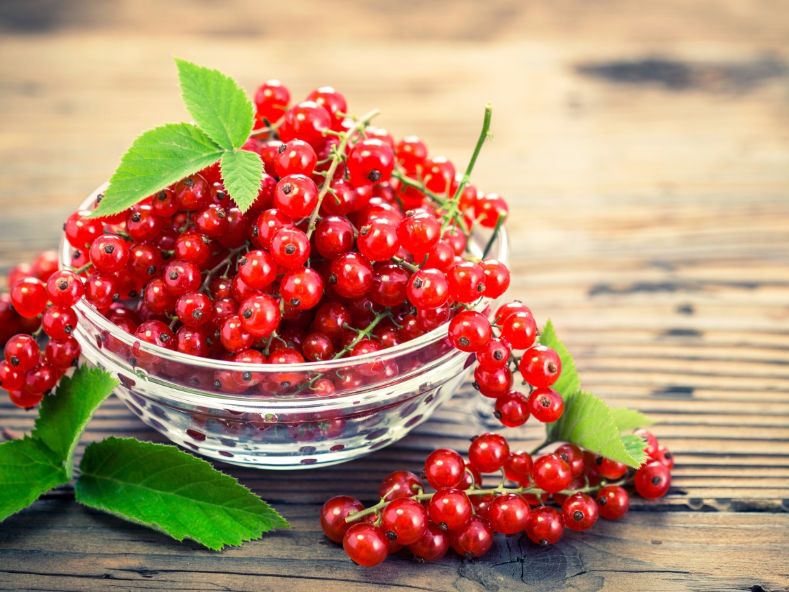 Красная смородина в стеклянной миске на столе 