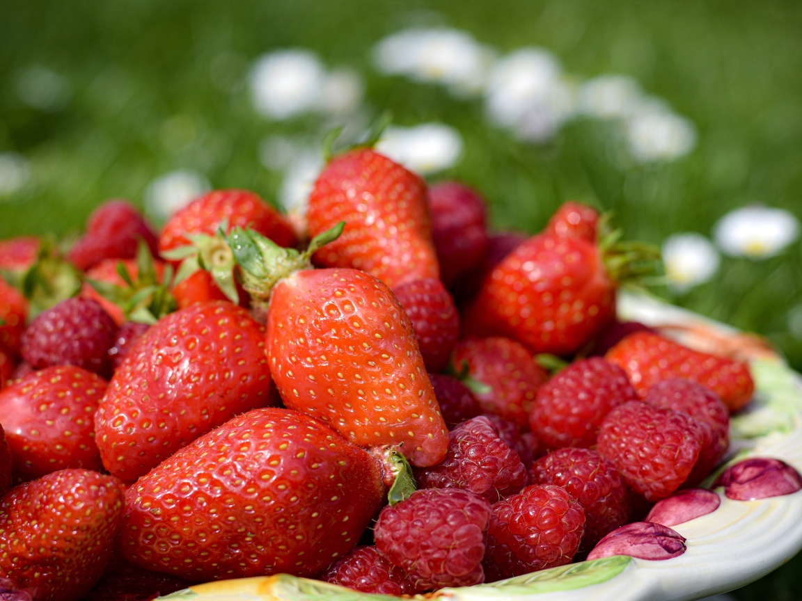 Спелая малина с ягодами клубники в тарелке 