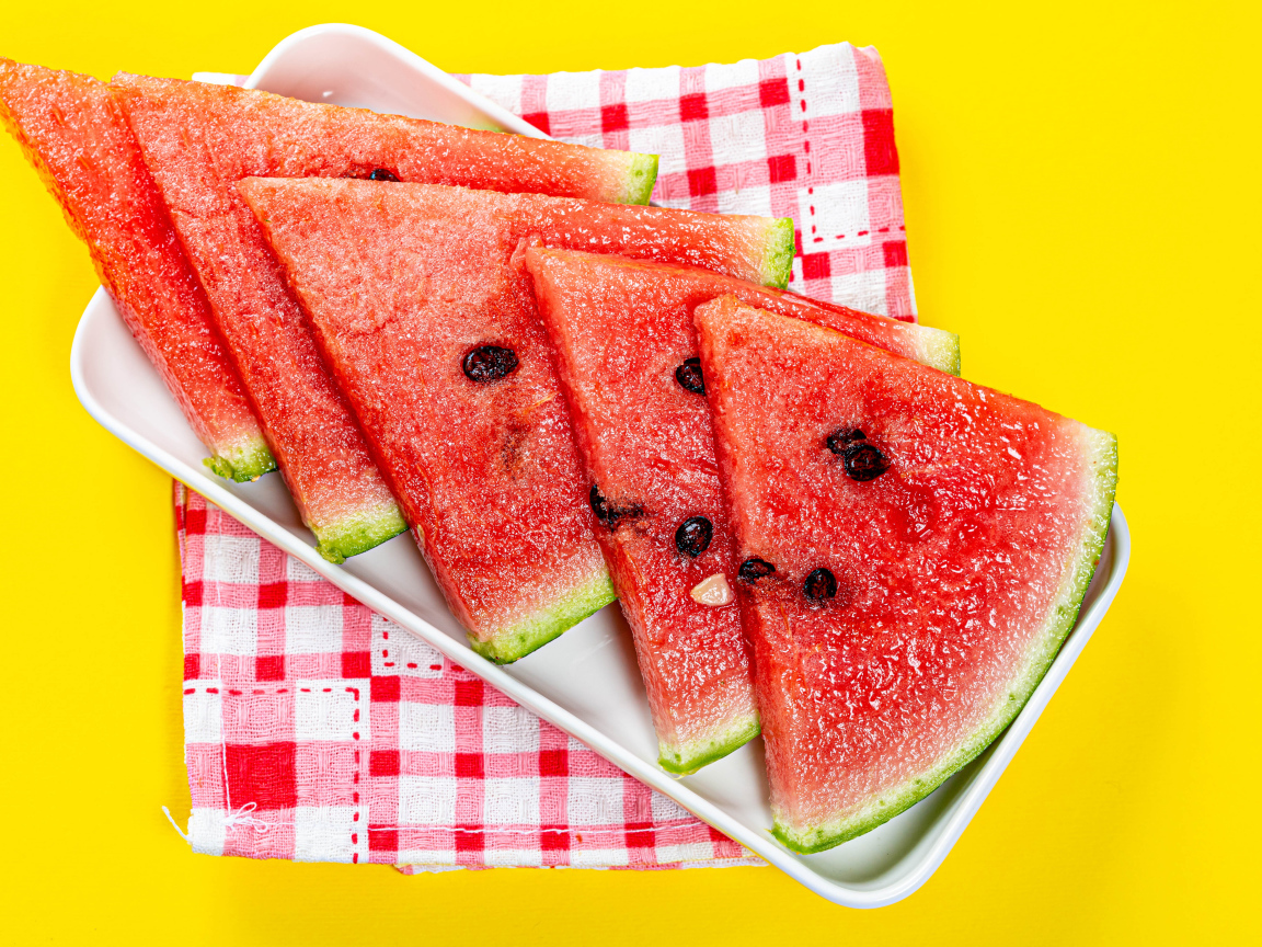 Кусочки сочного арбуза в тарелке на желтом столе