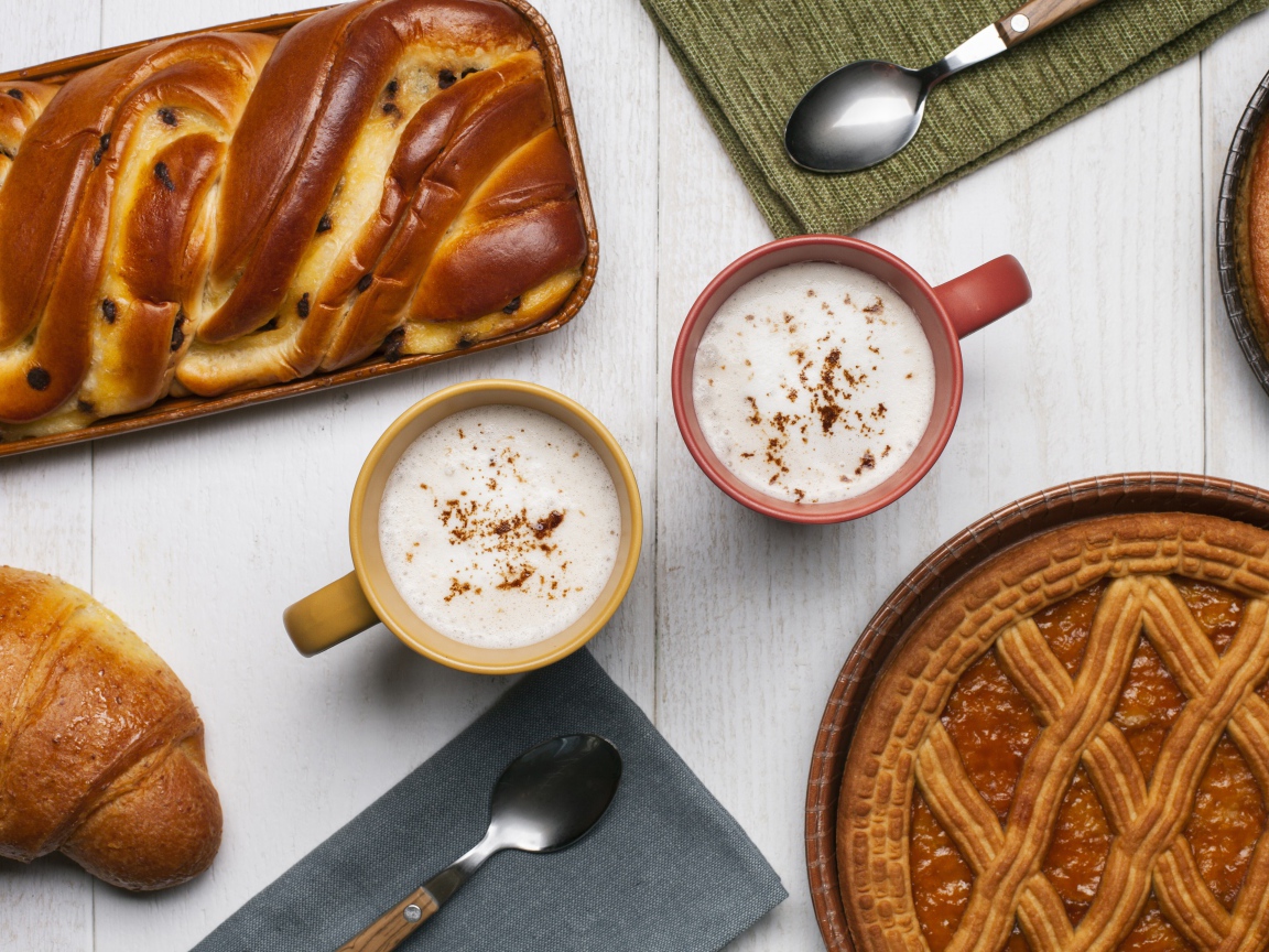 Свежая выпечка и две кружки молока на столе