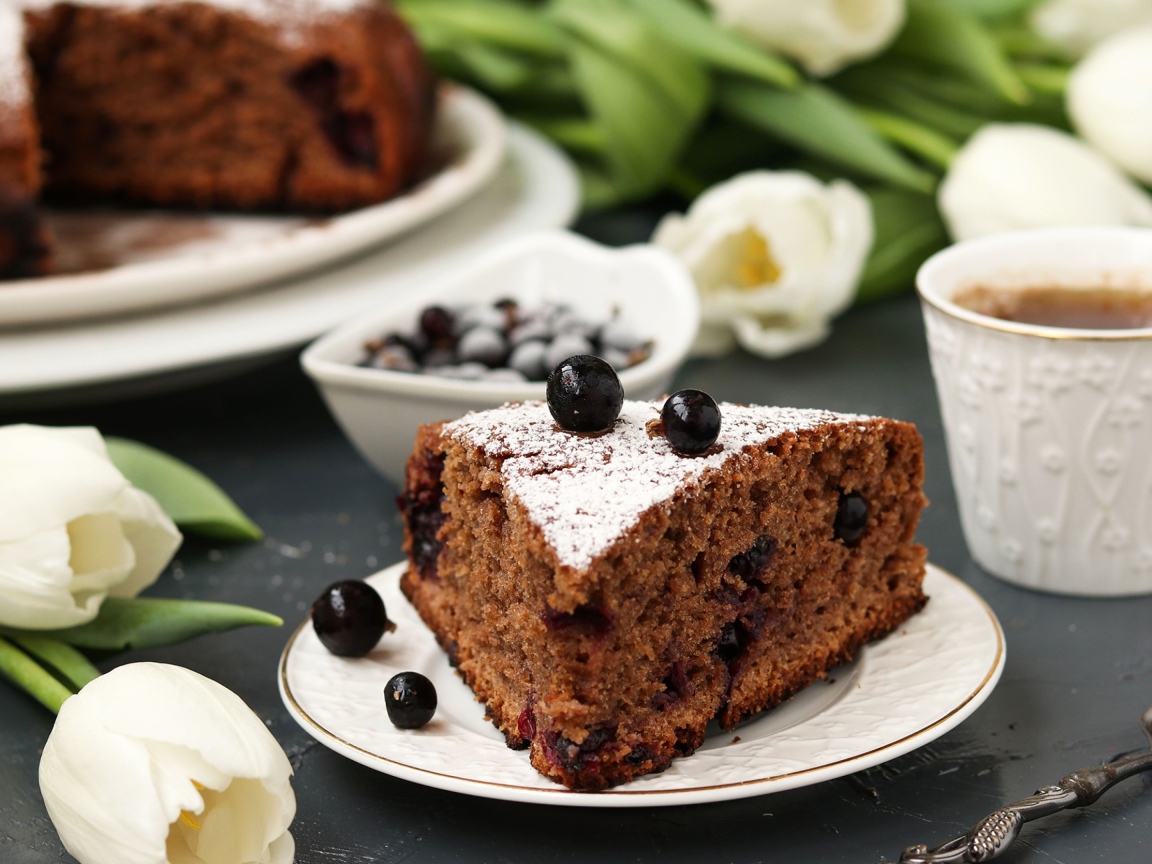 Кусок пирога со смородиной на столе с тюльпанами 